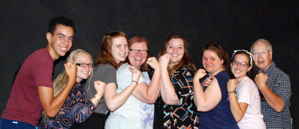 Production team members and workshop cast members pose with the Rosie the Riveter strong arm