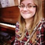 Ginny Henderson, Instructor at Broadway Bound, is pictured in front of a piano and looks on with vast musical knowledge